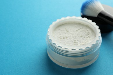 Rice loose face powder and makeup brush on light blue background, closeup. Space for text