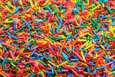 Photo of Bright colorful sprinkles as background, closeup. Confectionery decor