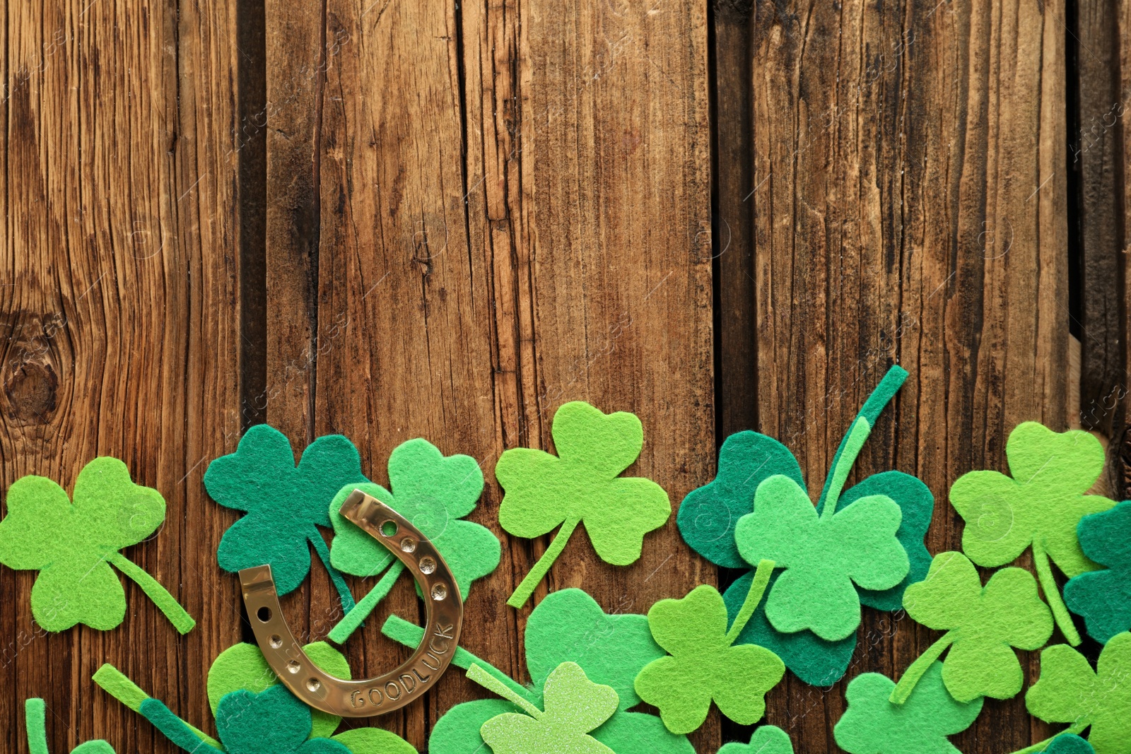 Photo of Flat lay composition with clover leaves and horseshoe on wooden background, space for text. St. Patrick's day