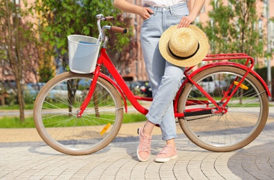 Photo of Young woman near modern color bicycle outside, closeup