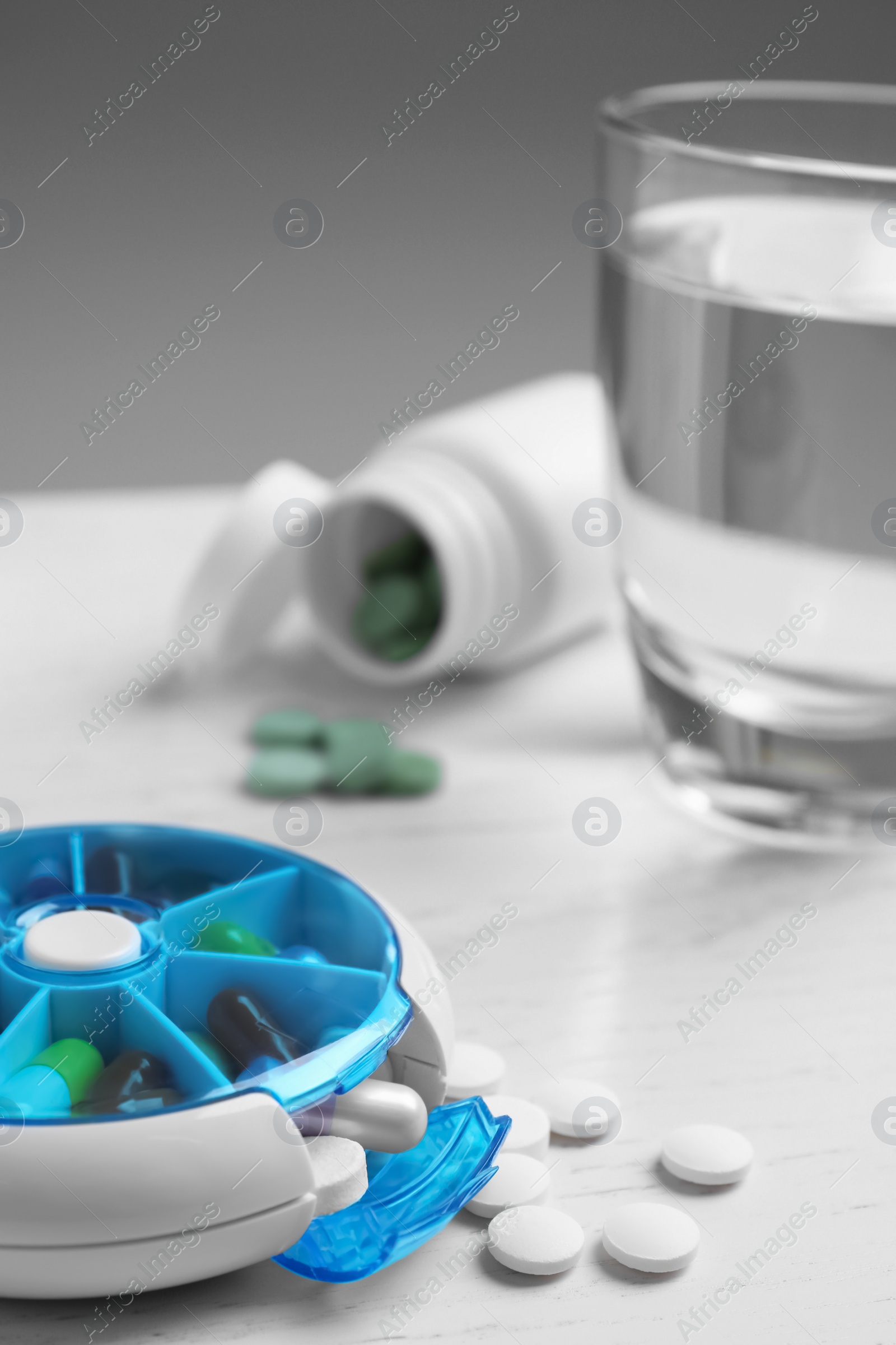 Photo of Pill box with medicaments on white wooden table, closeup