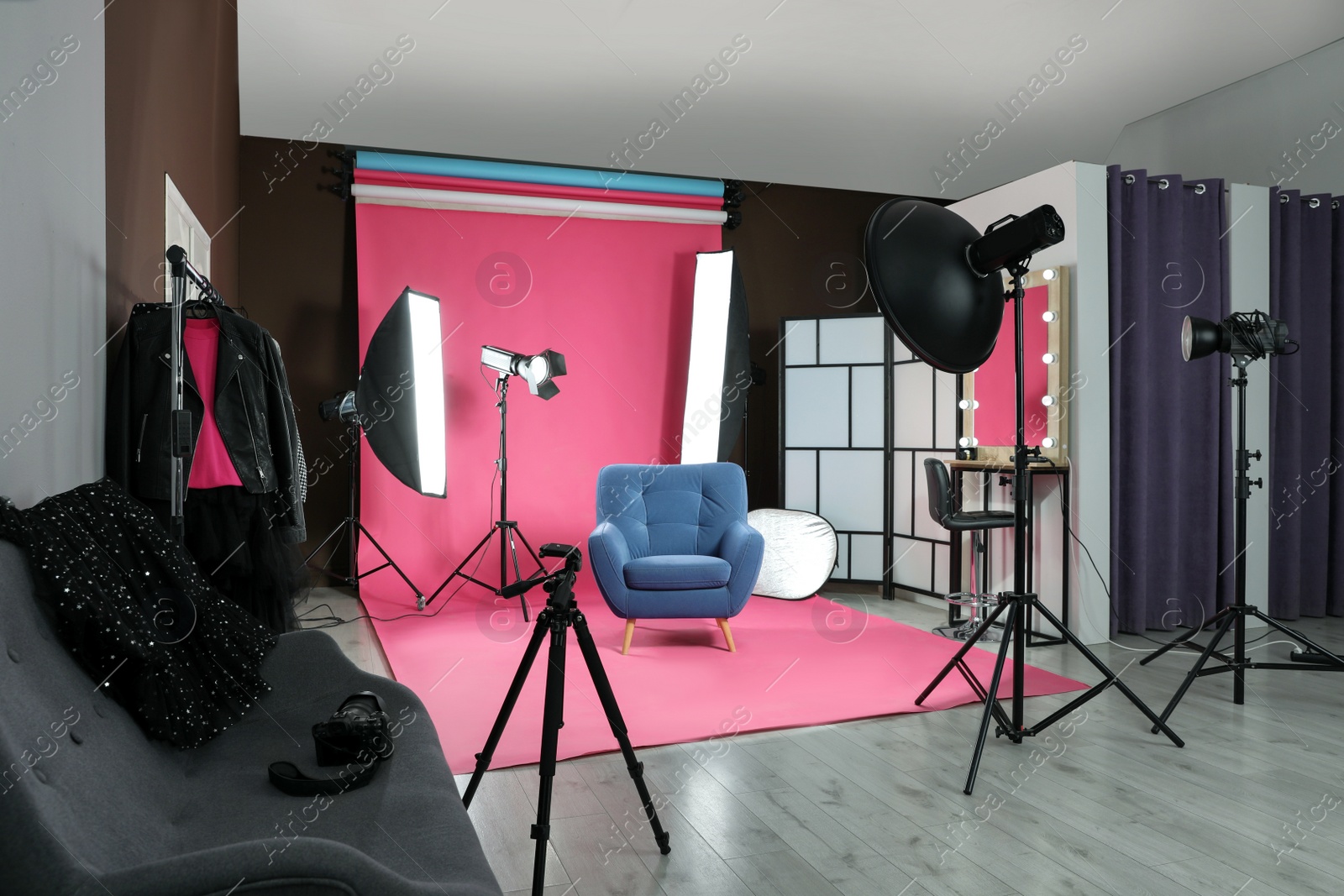 Photo of Stylish blue armchair in photo studio with professional equipment