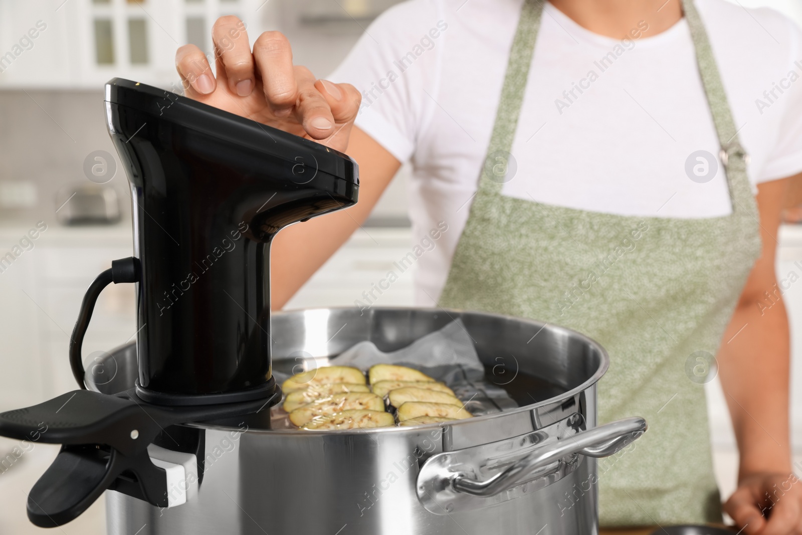 Photo of Woman using thermal immersion circulator in kitchen, closeup. Sous vide cooking