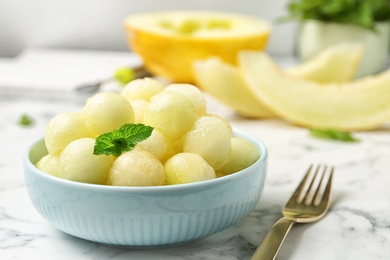 Photo of Plate of melon balls with mint on white marble table, closeup