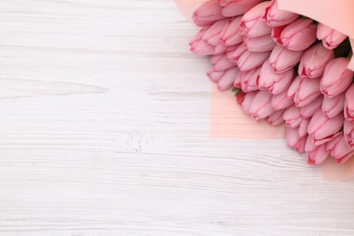 Bouquet of beautiful pink tulips on white wooden table, above view. Space for text