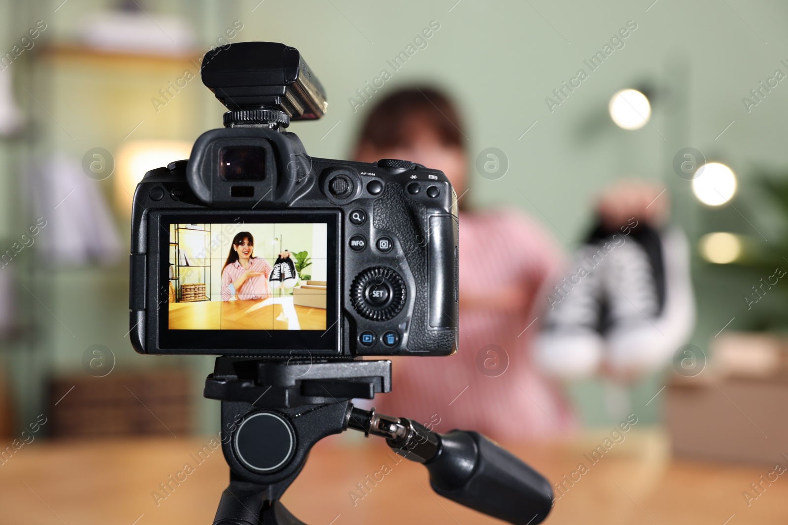 Photo of Fashion blogger recording video while talking about sneakers at home, focus on camera