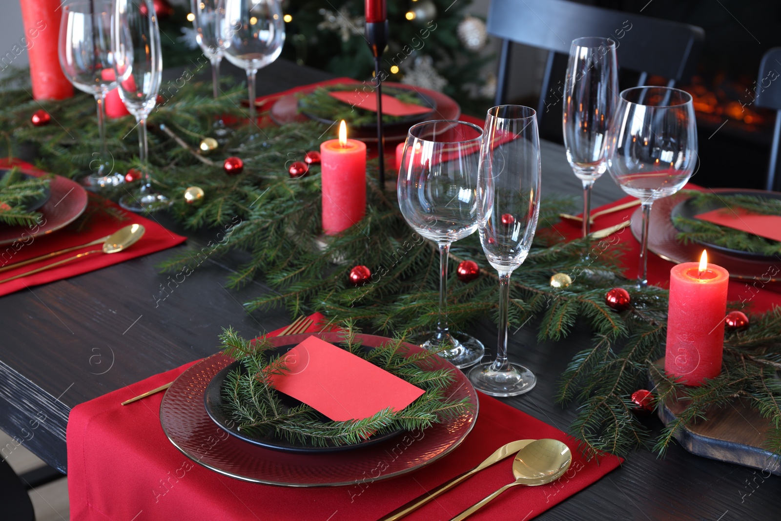 Photo of Elegant Christmas table setting with dishware and burning candles in festively decorated room