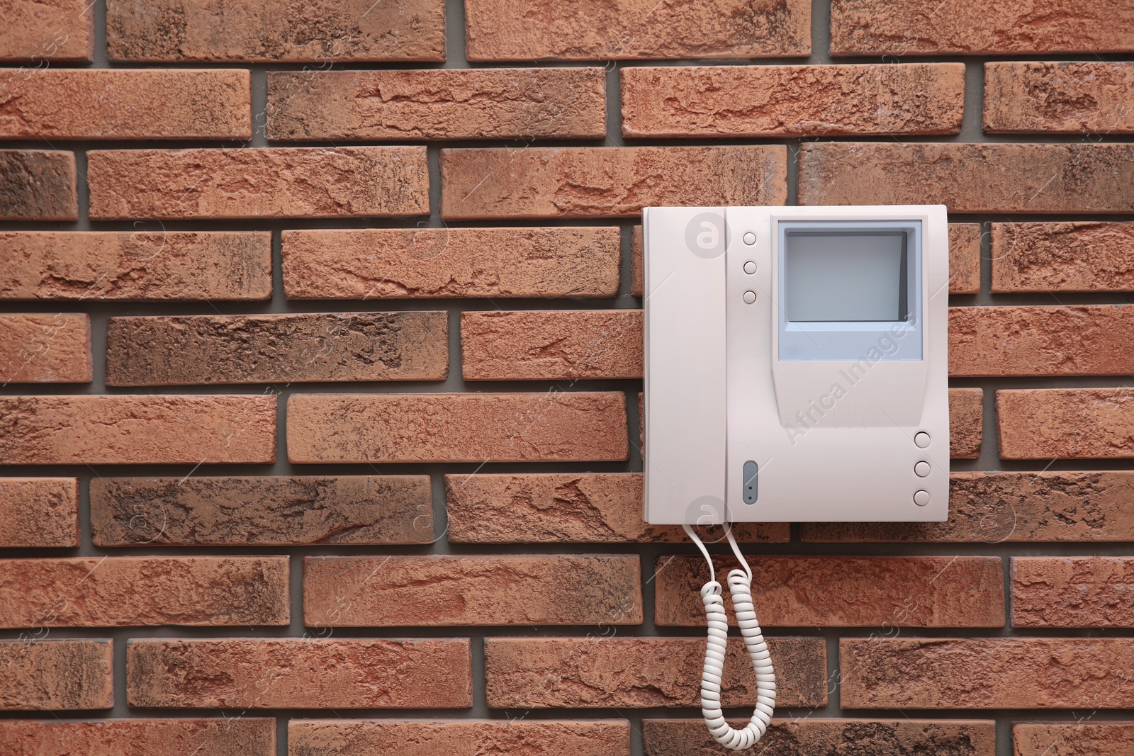 Photo of Modern intercom system with handset on red brick wall, space for text