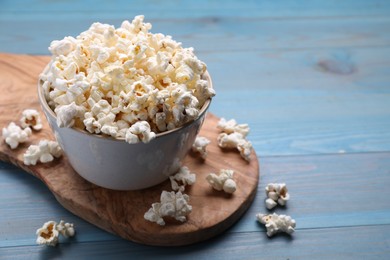 Photo of Tasty popcorn on light blue wooden table