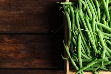 Photo of Fresh green beans in crate on wooden table, top view. Space for text