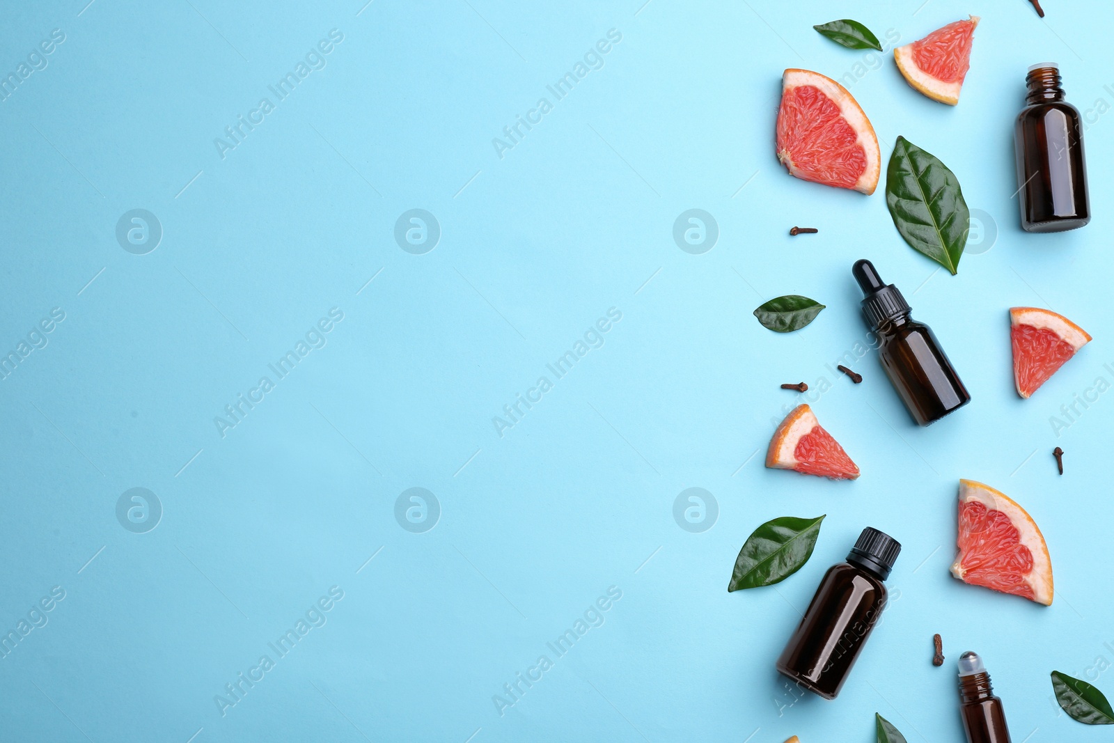 Photo of Flat lay composition with grapefruit slices and bottles of essential oil on color background, space for text