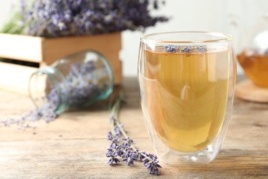 Photo of Fresh delicious tea with lavender in glass on wooden table. Space for text