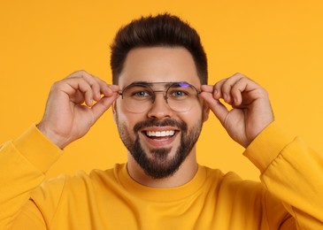 Handsome man wearing glasses on orange background