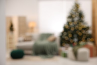 Photo of Christmas tree in room decorated for holiday, blurred view. Festive interior