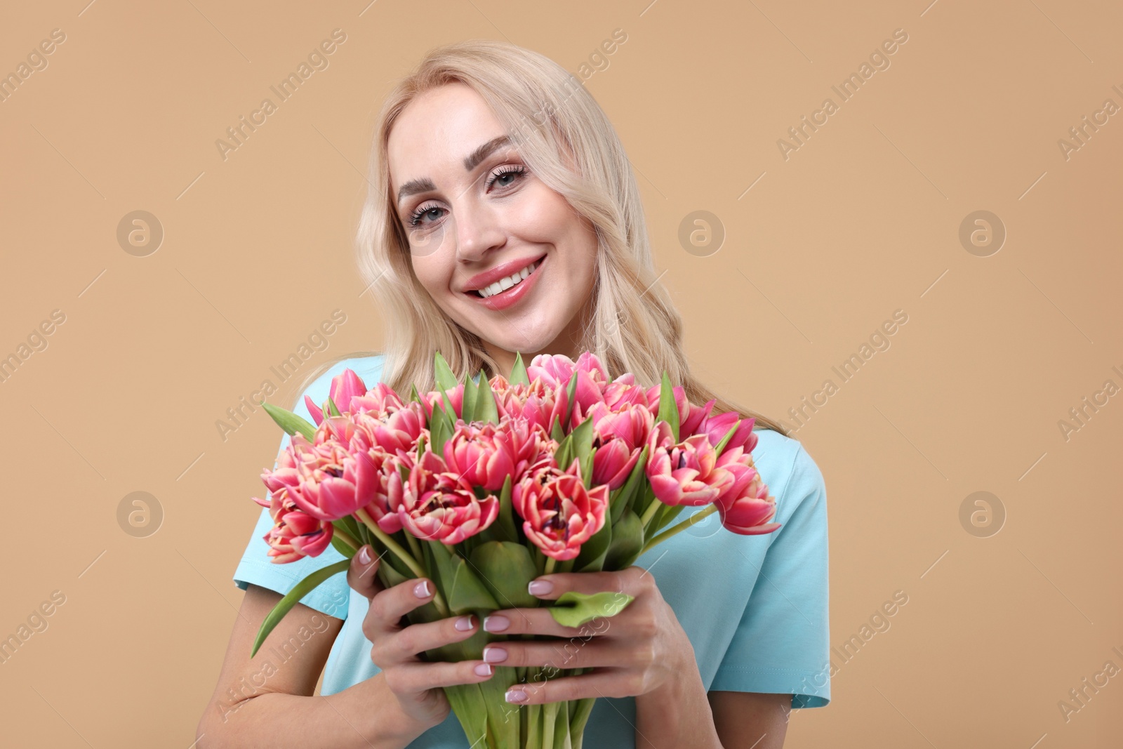 Photo of Happy young woman with beautiful bouquet on beige background