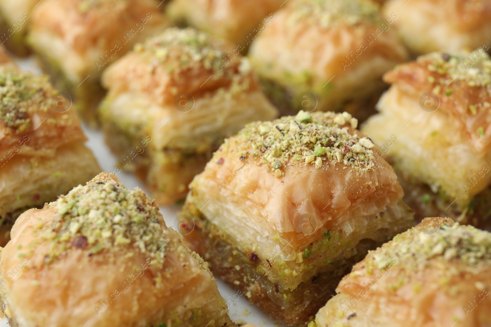 Photo of Delicious fresh baklava with chopped nuts on white table, closeup. Eastern sweets