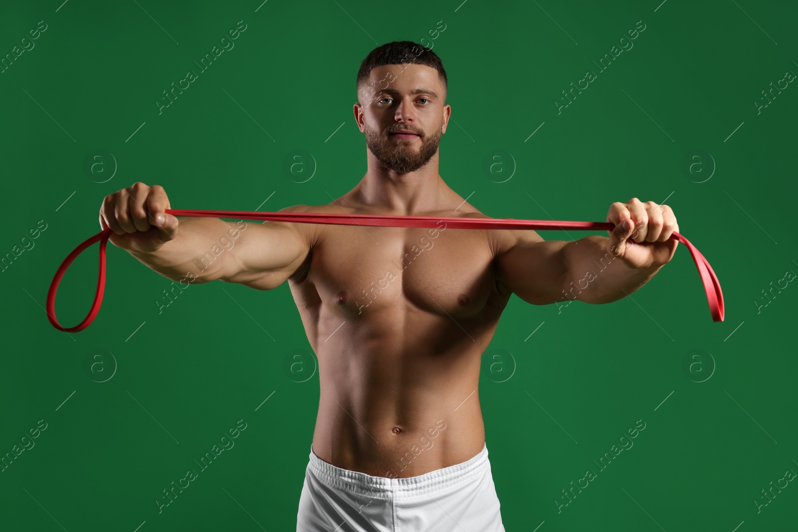 Photo of Muscular man exercising with elastic resistance band on green background