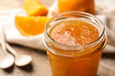 Photo of Homemade delicious orange jam on table, closeup view