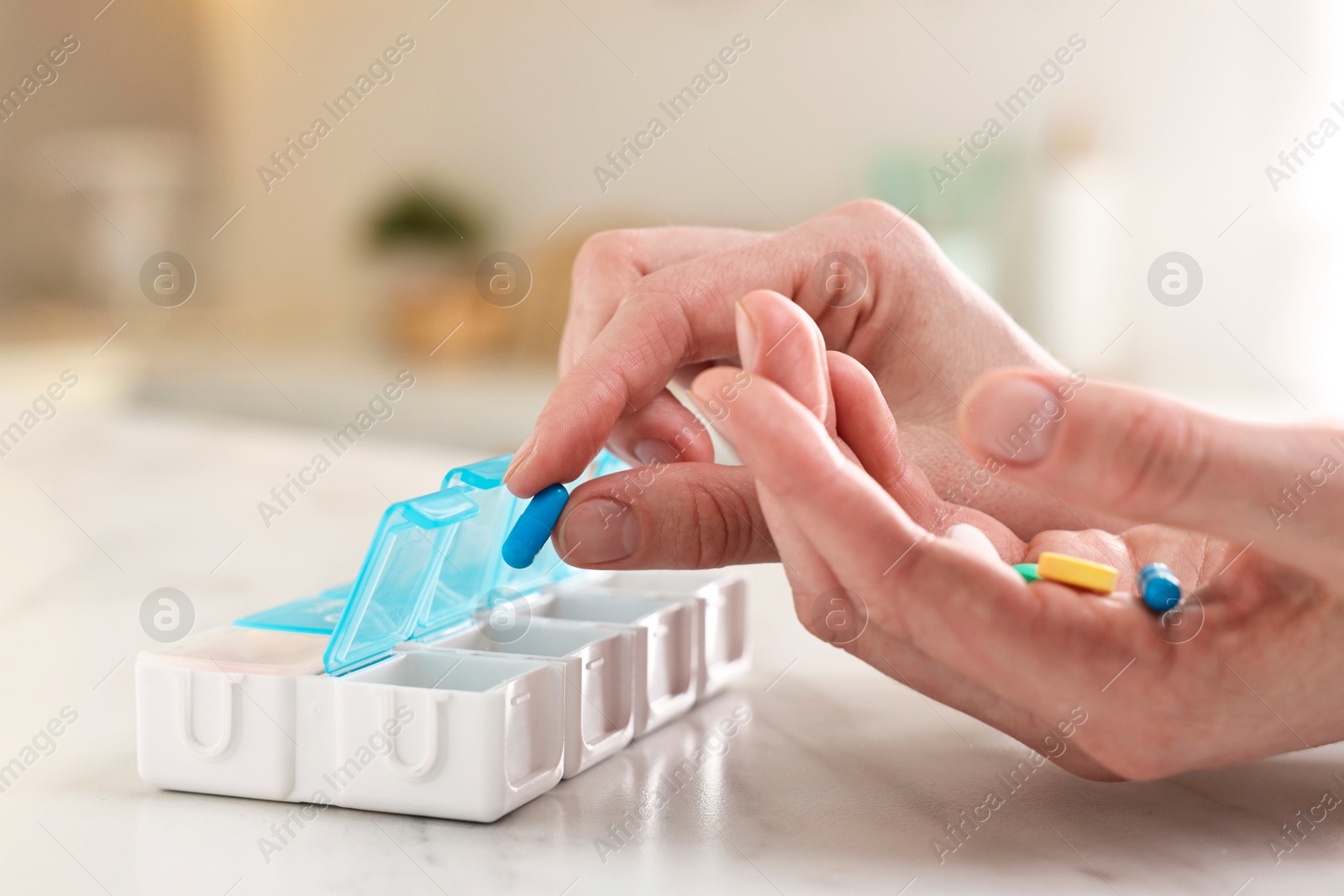 Photo of Woman with pills and organizer at white marble table, closeup