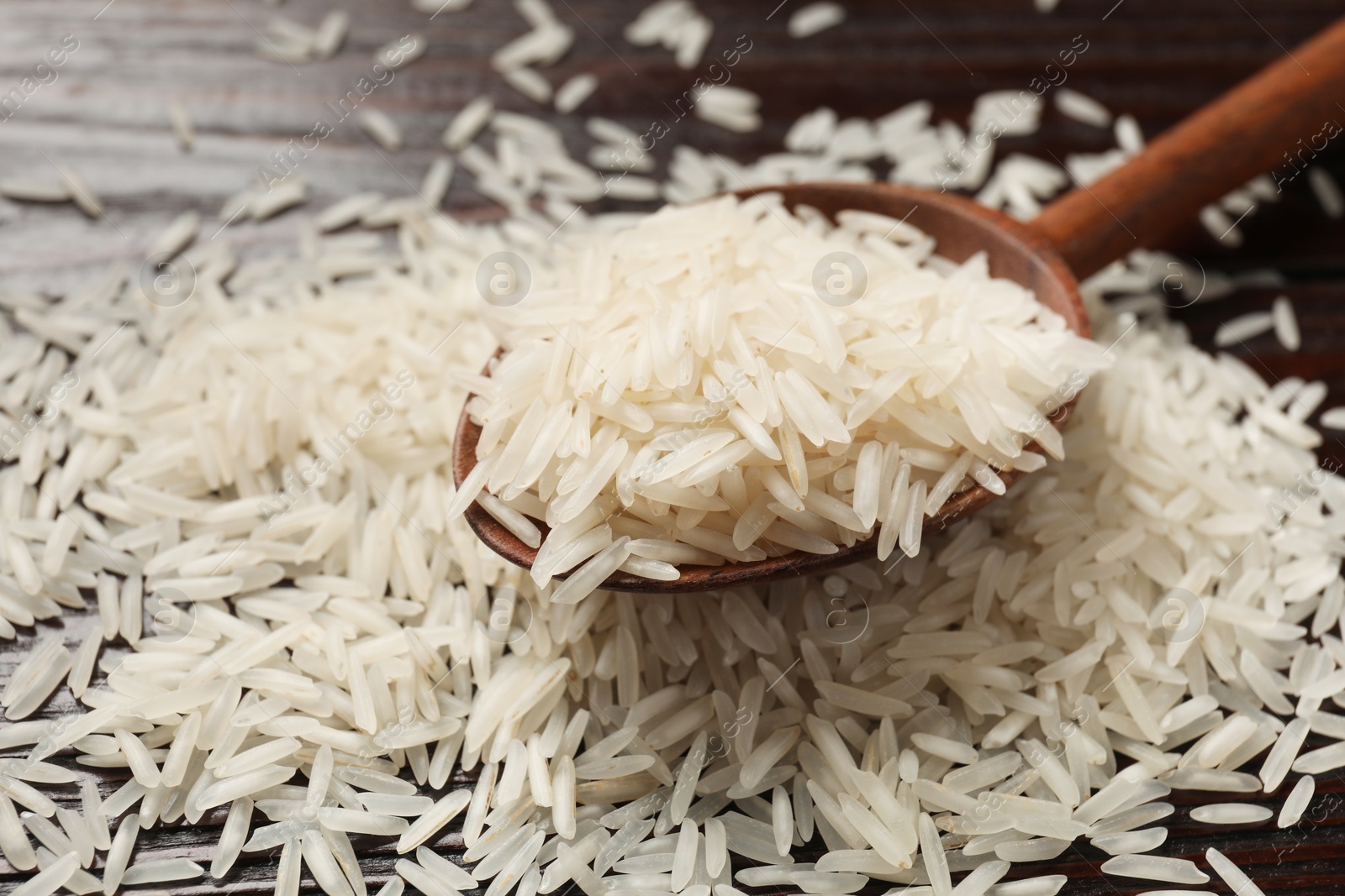 Photo of Raw basmati rice and wooden spoon on table, closeup