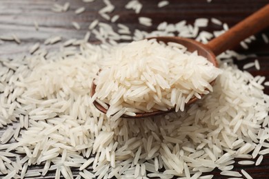 Raw basmati rice and wooden spoon on table, closeup