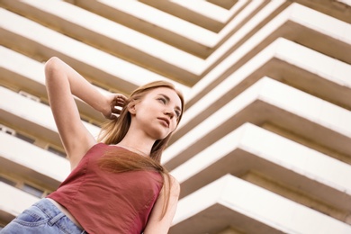 Photo of Beautiful young woman at modern building, low angle view