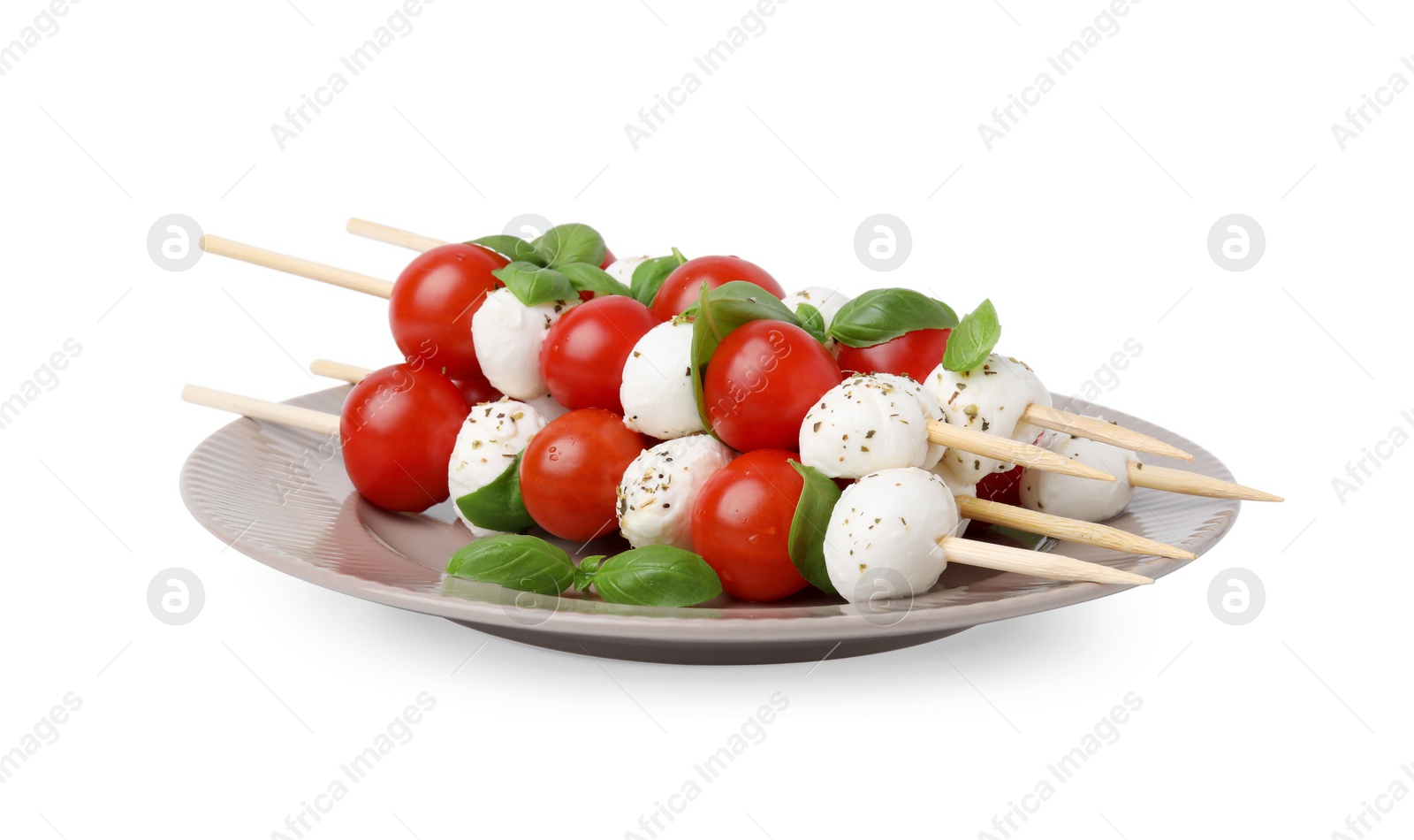 Photo of Plate of Caprese skewers with tomatoes, mozzarella balls, basil and spices isolated on white