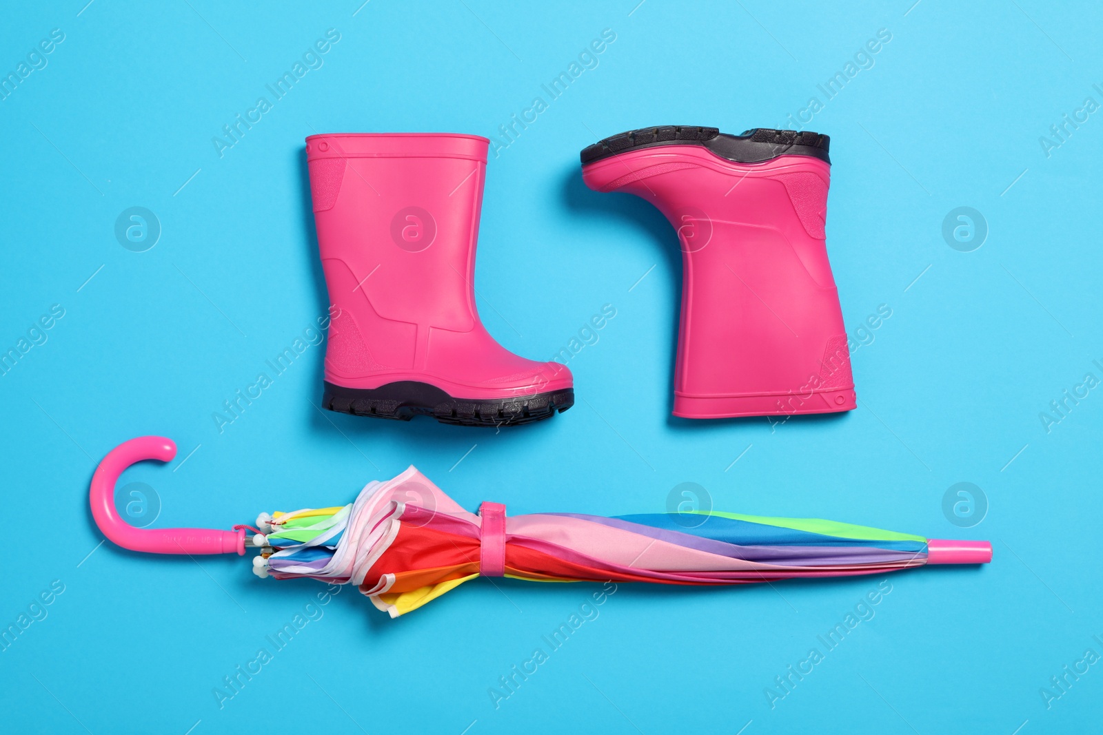 Photo of Flat lay composition with umbrella and rubber boots on color background