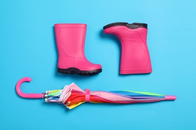 Photo of Flat lay composition with umbrella and rubber boots on color background