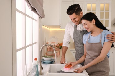 Photo of Happy lovely couple washing dishes in kitchen