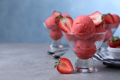 Photo of Delicious strawberry ice cream served on grey table. Space for text