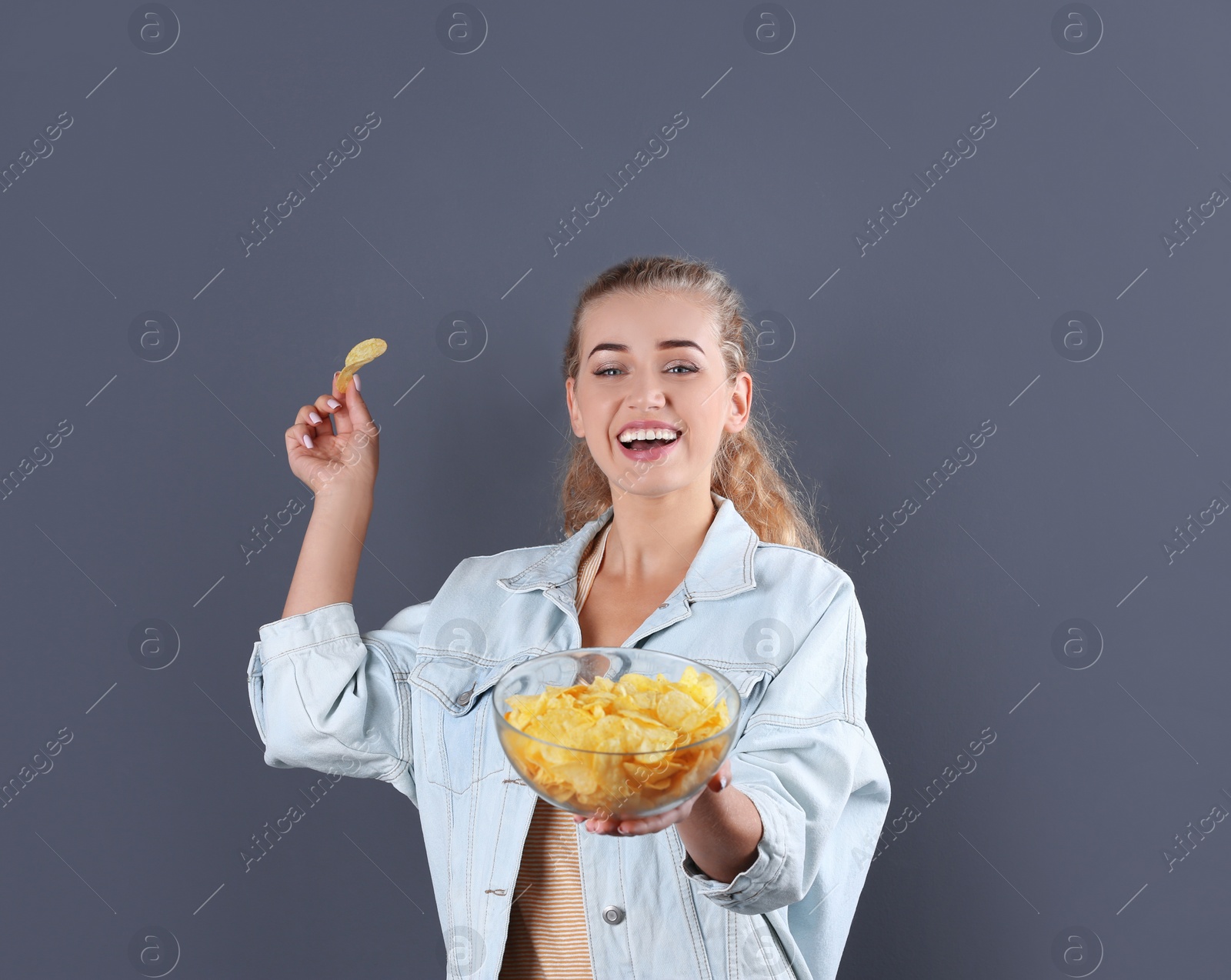 Photo of Woman with bowl of potato chips on grey background