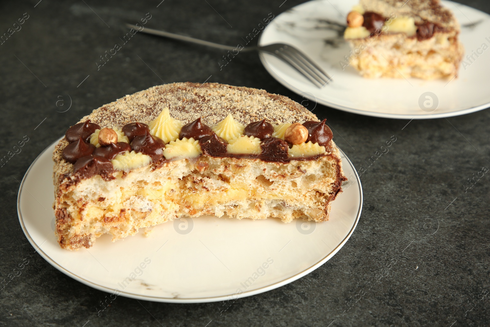 Photo of Delicious Kyiv Cake decorated with cream and hazelnuts served on black table, closeup