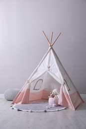 Photo of Cute child room interior with play tent near light grey wall