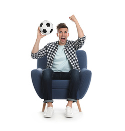 Handsome young man sitting in armchair and watching soccer match on white background