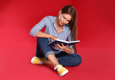 Photo of Beautiful young woman reading book on red background