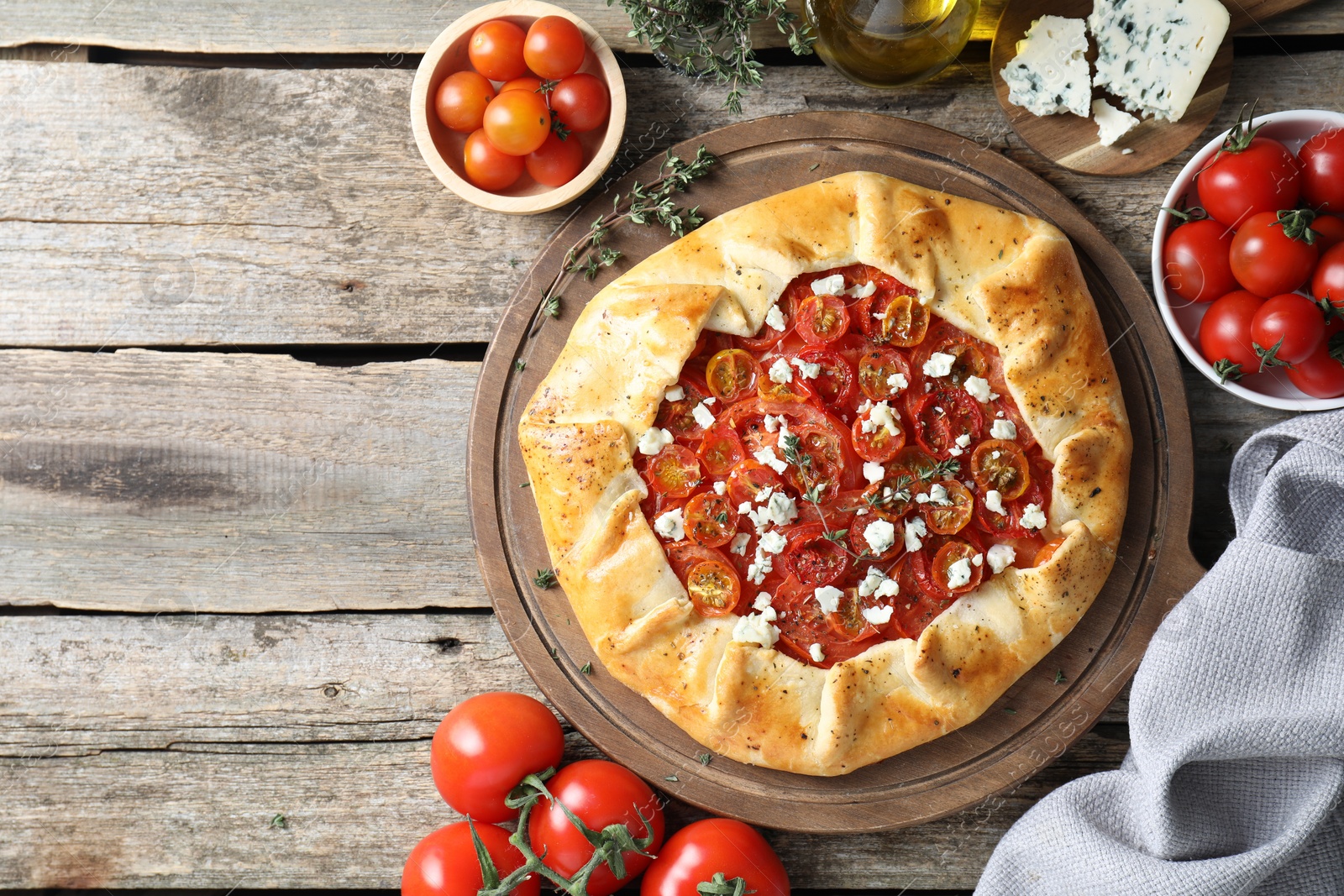 Photo of Flat lay composition of tasty galette with tomato and cheese (Caprese galette) on wooden table. Space for text