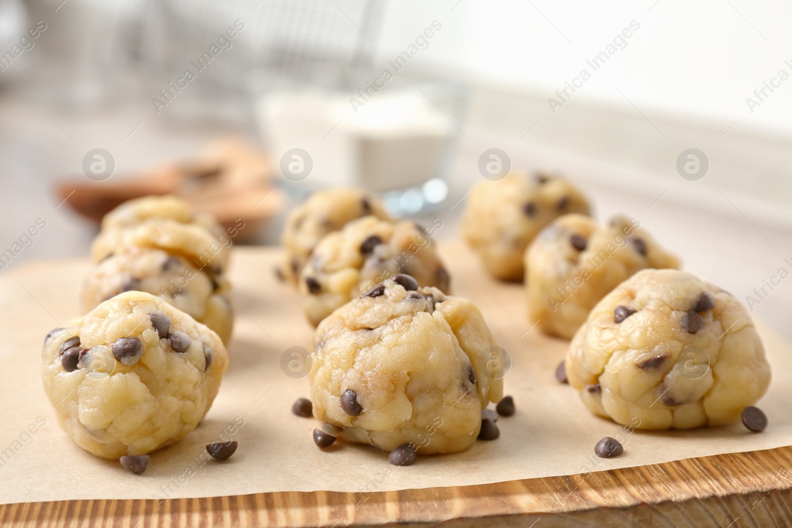 Photo of Raw cookie dough with chocolate chips on wooden board