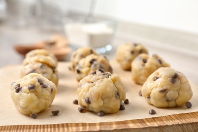 Photo of Raw cookie dough with chocolate chips on wooden board