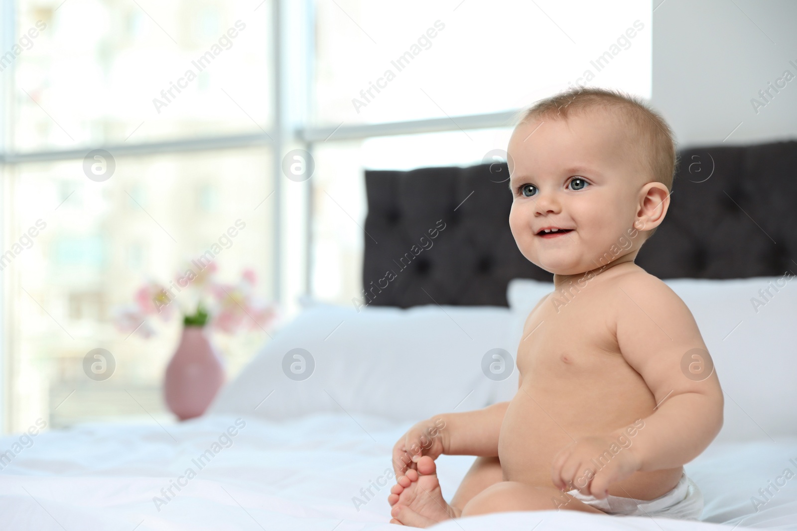 Photo of Cute baby in diaper on bed at home. Space for text