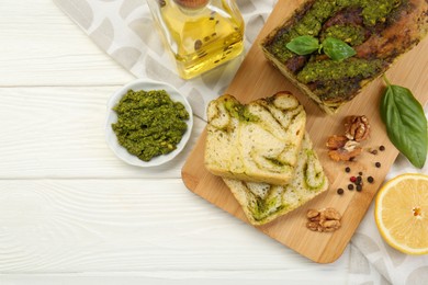 Photo of Freshly baked pesto bread with ingredients on white wooden table, flat lay. Space for text