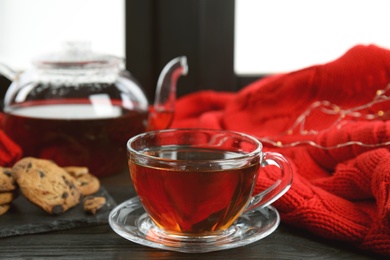 Photo of Cup of hot tea on window sill. Winter drink