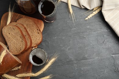 Photo of Delicious kvass, bread and spikes on black slate table, flat lay. Space for text