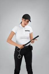 Female security guard with police baton on color background