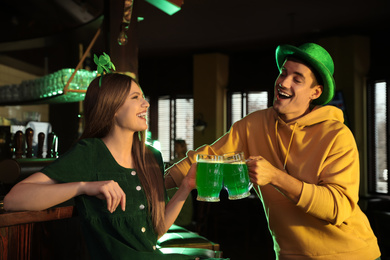 Young woman and man toasting with green beer in pub. St. Patrick's Day celebration