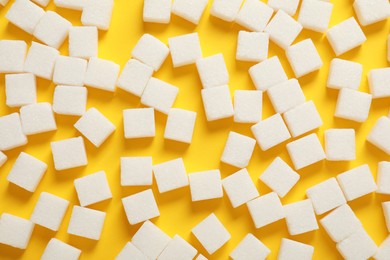 Photo of White sugar cubes on yellow background, flat lay