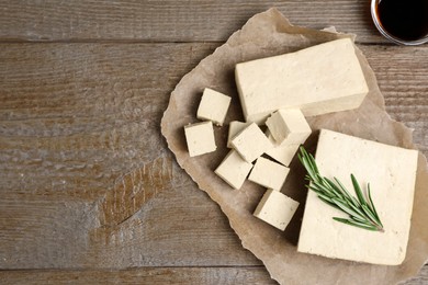 Photo of Delicious tofu with rosemary and soy sauce on wooden table, flat lay. Space for text