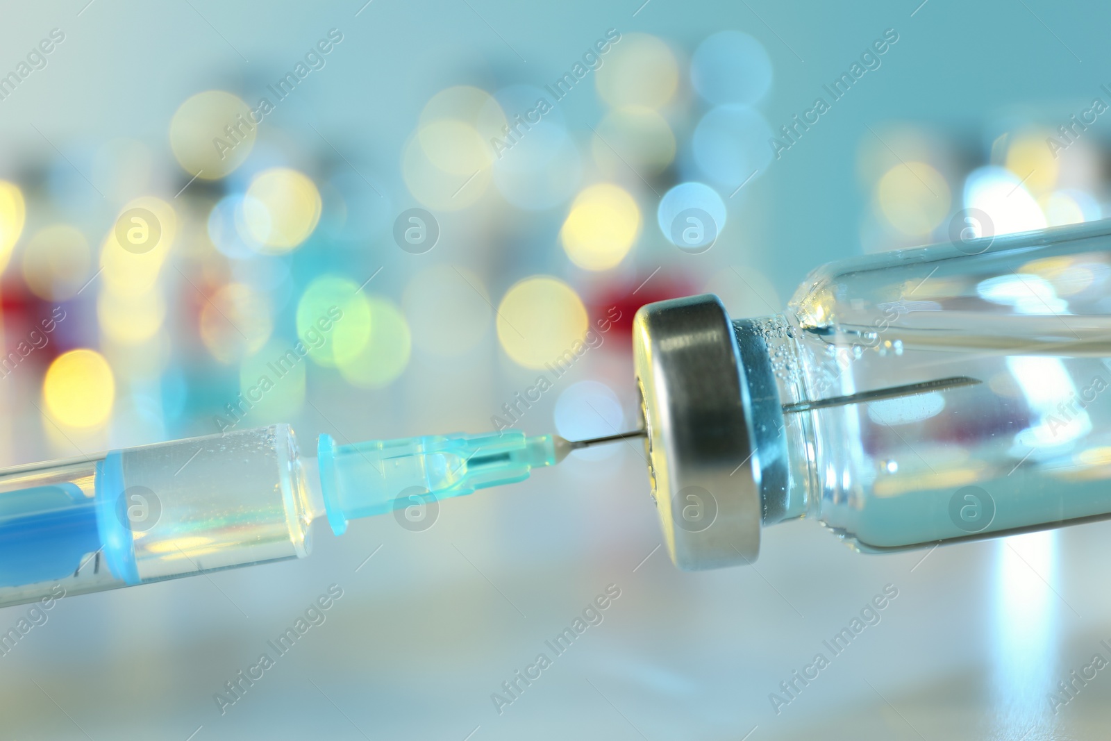 Photo of Filling syringe with medication from vial against blurred background, closeup. Vaccination and immunization