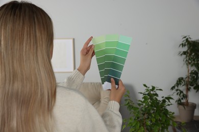 Photo of Woman with paint chips choosing color for wall in room. Interior design