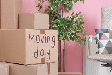 Photo of Cardboard boxes and household stuff in empty room. Moving day